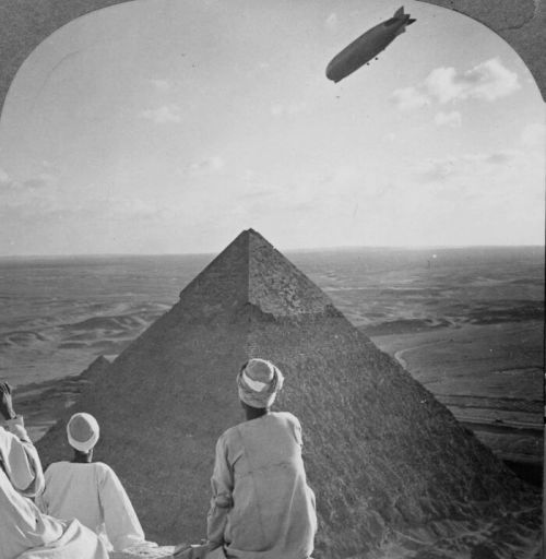 Egyptian Men Watch As The Graf Zeppelin Floats Over The Great Pyramids Of Giza, Egypt, While Atop Th