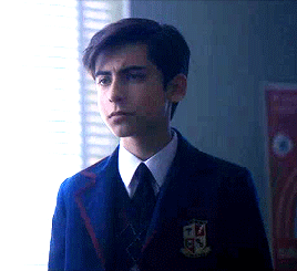 Gif 4: Five stands in front of Dot's desk. His face is carefully guarded, with an air of bored neutrality. Only his jaw clenching at Dot's word betray his underlying feelings.