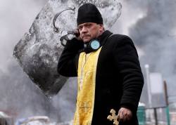 chingizhobbes:   A priest holds a cross and shield during clashes between anti-government protesters and riot police in Kiev, Ukraine, on February 20.    