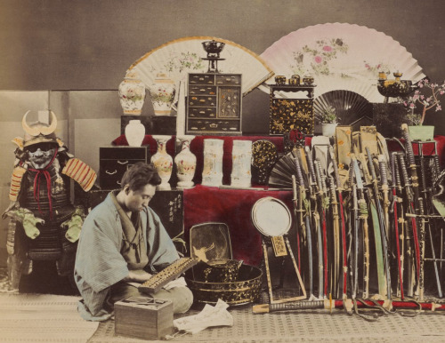 Hand-colored photo of a merchant doing math on an abacus in his antique shop.  Circa 1888, Japa