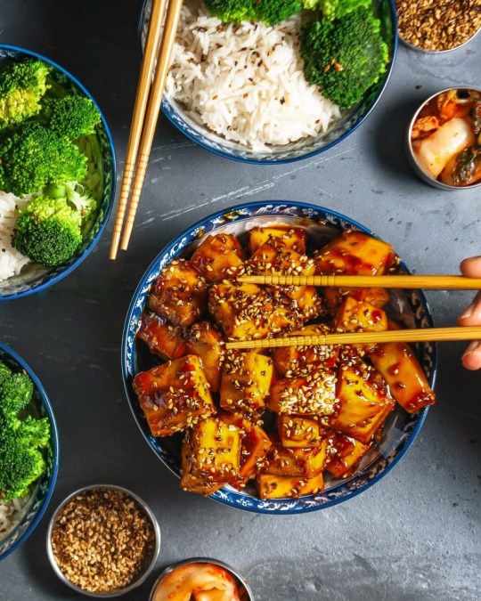 Top down view of an easy recipe with tofu. Bowls of sticky orange sesame tofu, rice and brocolli. 