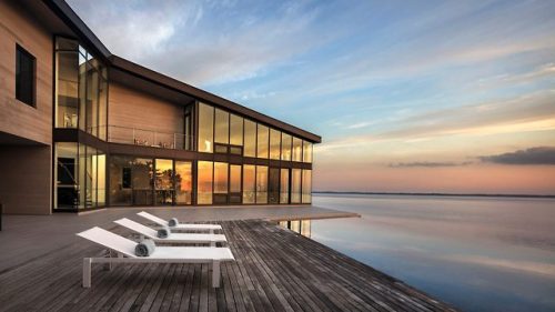 An opening cuts through this Hamptons residence by Marvel Architects, revealing an infinity pool and