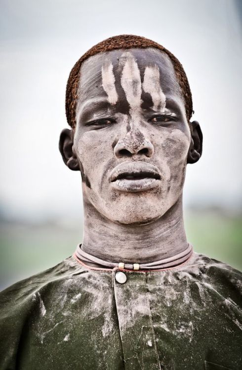Africa | A Mundari male covered in ash and orange hair bleached in the sun from washing it in cow ur