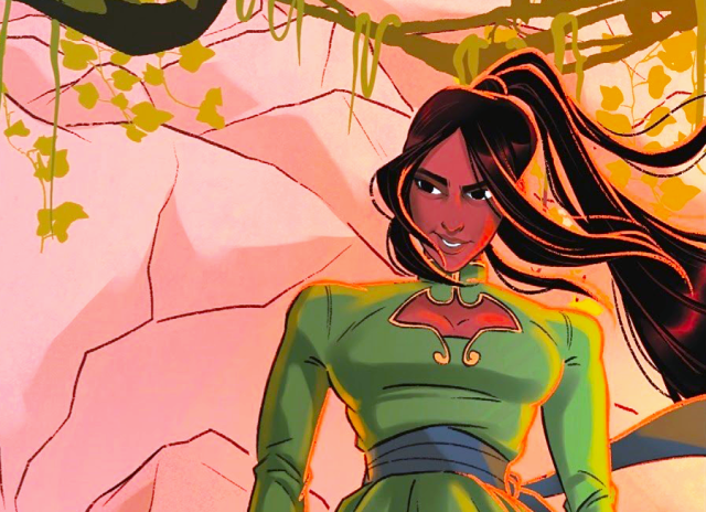 Talia from the waist up. She's wearing a green top with gold trim and a blue belt, and her long hair is in a ponytail. The background is a cliff wall.