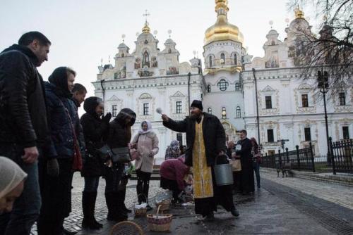 globalchristendom:A priest blesses the faithful as they collect cakes and painted eggs for Easter at