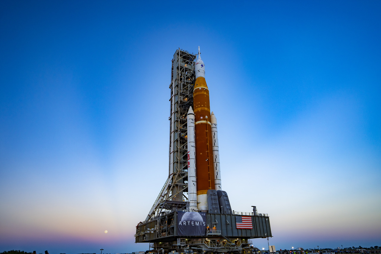 The full Moon shines on the SLS rocket and Orion spacecraft at sunset.