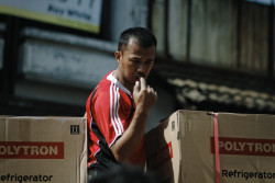 Man unloads boxes of polytron refrigerator. Bandung, Indonesia