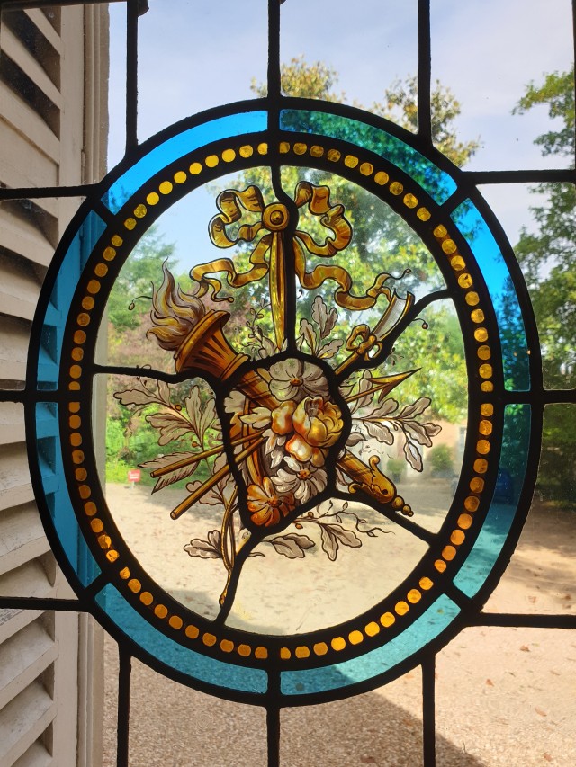 a stain glass window depicting a torch, flowers and arrows 