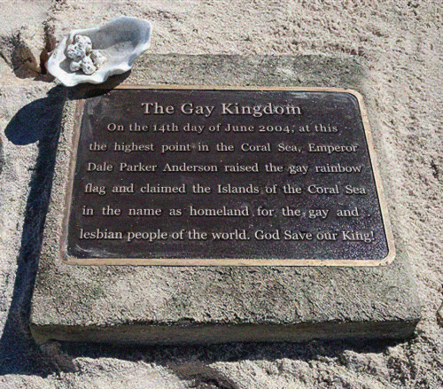 Metal plaque on a beach reading: The Gay Kingdom. On the 14th day of June 2004, at this the highest point in the Coral Sea, Emperor Dale Parker Anderson raised the gay rainbow flag and claimed the Islands of the Coral Sea in the name as homeland for the gay and lesbian people of the world. God Save our King!