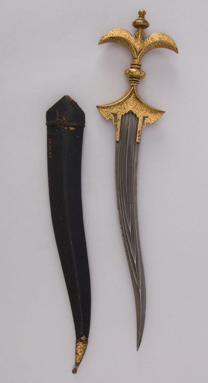 art-of-swords:Chilanum Dagger with SheathDated: 18th centuryCulture: IndianMedium: Iron, gold, leatherMeasurements: H. with sheath 16 3/8 in. (41.6 cm); H. without sheath 15 1/4 in. (38.7 cm); H. of blade 10 13/16 in. (27.5 cm); W. 3 9/16 in. (9 cm);
