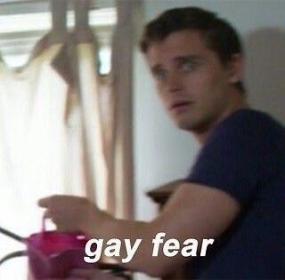 A blurry photo of Antoni from Queer Eye. He looks terrified and worried, holding a small gift bag. The caption at the bottom of the picture reads "Gay fear"
