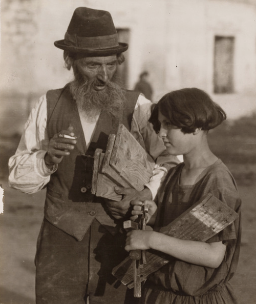 Jewish carpenter and his granddaughter carrying short pieces of wood and hammers in Czortkow, Poland