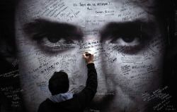 realidad-retorcida:   Un hombre escribe en un mural frente a la clínica en Buenos Aires, el día del fallecimiento de Gustavo Cerati. 2014.  