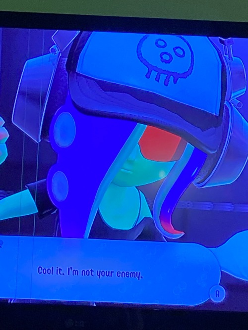 a green-skinned octoling with red glasses, large headphones and a hat adorned on their head as the chat bubble is unnamed but states "cool it. im not your enemy." the character later introduces themself as Acht