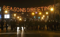 thepoliticalfreakshow:  This Is AmeriKKKa: All this to protect a killer? Seasons Greetings, indeed, America. What appears to be absurd juxtaposition is this holiday reality for the people of #Ferguson. 