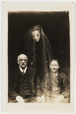 weirdvintage:  Elderly couple with female “spirit”, c. 1920 by William Hope, “spirit photographer” Hope’s “Spirit Photography” work gained momentum after WWI, when many people were desperate to find evidence of loved ones living beyond