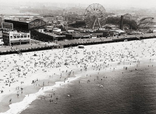 Sunbathers on the beach. Coney Island, Brooklyn, 1953. Ferris Wheel and Cyclone Roller Coaster in th