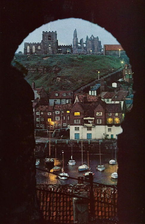 vintagenatgeographic: Bleak ruins of an abbey loom above the harbor at Whitby in Yorkshire, England 