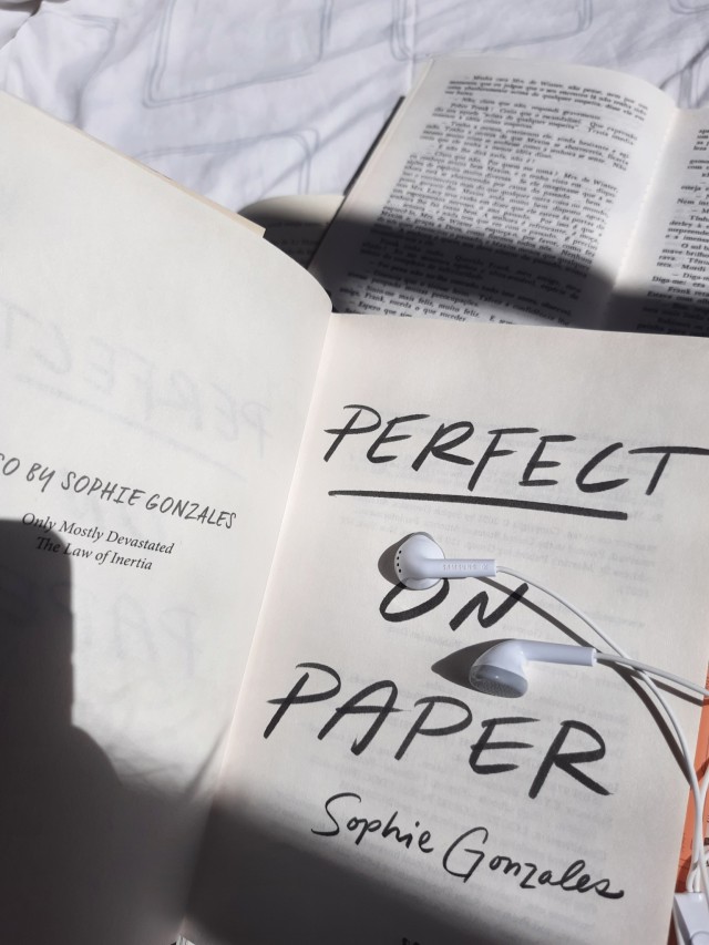 a close-up of the title page of Perfect On Paper with earphones next to the title. 