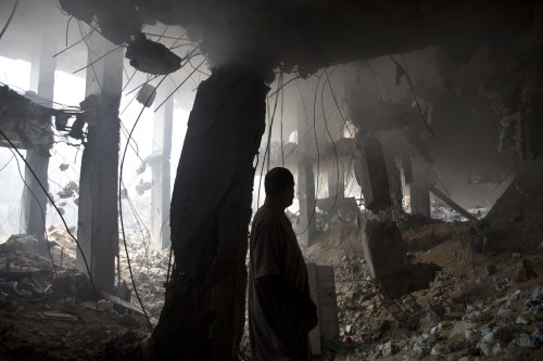 A Palestinian man inspects the rubble of a destroyed store located on the ground floor of a building