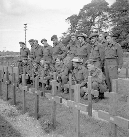 Major J.M. Figott and members of his company of the Royal Hamilton Light Infantry kneeling at the gr