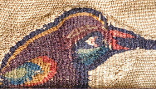 Textile fragment of undyed linen furnishing fabric bearing a tapestry motif of a bird in coloured wo