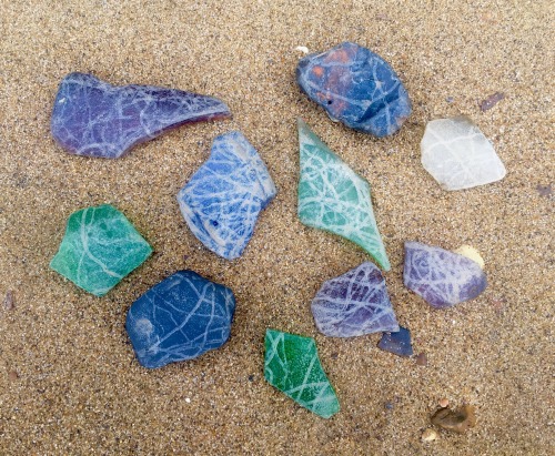 Pieces of coloured glass, each with striations/markings, possibly caused by muddy incoming/outgoing 