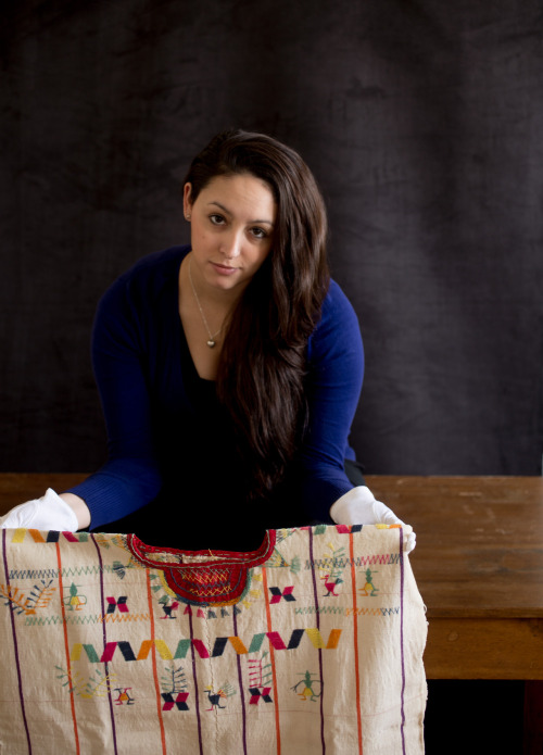 Allie Stone - Collections Assistant and Imaging Specialist in Insects, holding a cotton woven tunic from Guatemala, an item from the Economic Botany Collections.