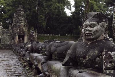 Statues of ancient khmer warrior heads carry giant snake decorating bridge to Bayon at Angkor Wat complex, Siem Reap, Cambodia.