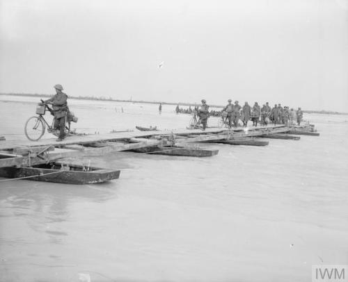 British cyclists, followed by Austro-Hungarian prisoners carrying wounded, crossing the river Piave 