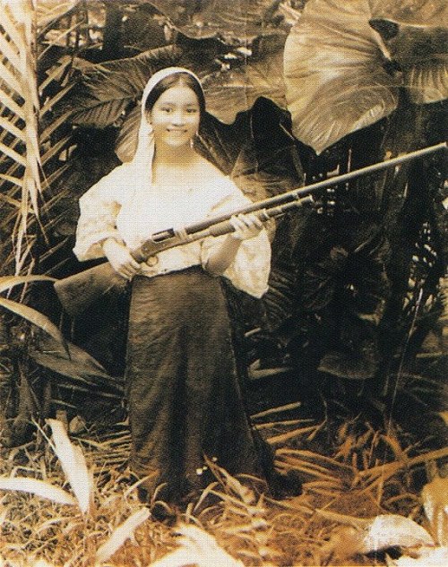 Filipina from the Batangas province posing with a M1897 Shotgun, early 20th century.