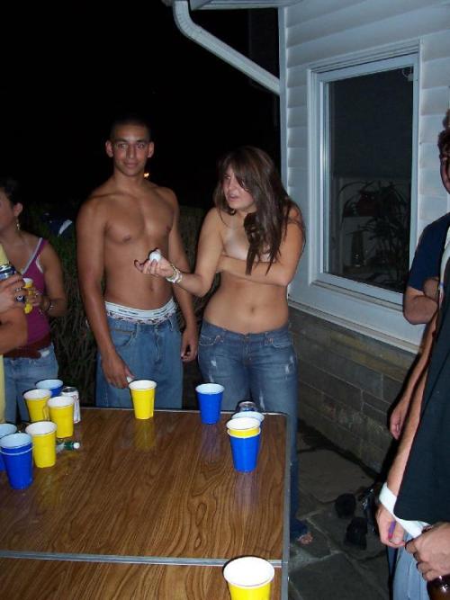 Two girls playing backyard strip beer pong, both end up topless as a result.