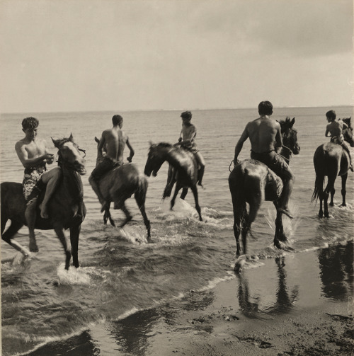 Men on horseback run through the surf in Tahiti, 1922. Photograph by Edward Burton MacDowell, Nation