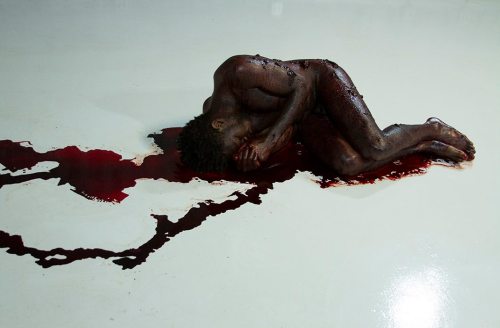 raveneuse:  Carlos Martiel,   Simiente, 2014.   “I lay in fetal position with my body covered of human blood, donated by immigrants from Mexico, Estonia, Italy, Venezuela, England, South Korea, as well as the United States.”  