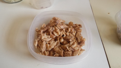 a plastic bowl of boneless, skinless canned salmon. It has been flaked.
