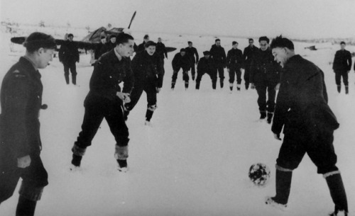 Pilots of the No 151 Wing British Royal Air Force play soccer in front of a Hurricane fighter aircra