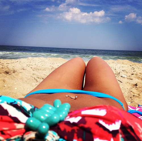 Sun beach bikini body woman with toned abs and slim legs tanning