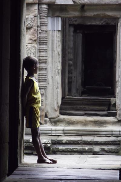 Boy in a colonnaded corridor in a temple in Angkor Wat, Cambodia.