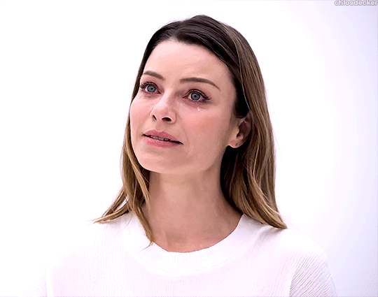 A gif of Chloe Decker clad in all white, looking forward with a hopeful expression. A single tear falls down her cheek.