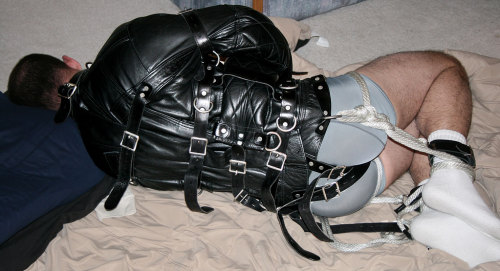strappedown:  I absolutely love me a leather straitjacket. This photo is of one of the first times I enjoyed being strapped in a leather straitjacket. Needless to say I fell head over heels in love.   Once you’ve felt its soft, supple, padded, leathery,