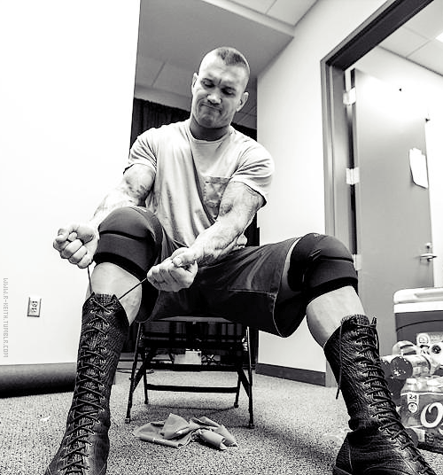 rwfan11:  Randy Orton - lacing up his boots ( I guess he wears those shorts over his trunks until it’s time to go to the ring, because there’s no way he’s getting those tiny trunks over those big boots!) … And I’m not sure what that piece