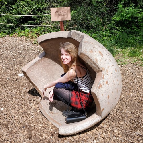 A woman crouching inside half an eggshell. Staten Island Zoo.