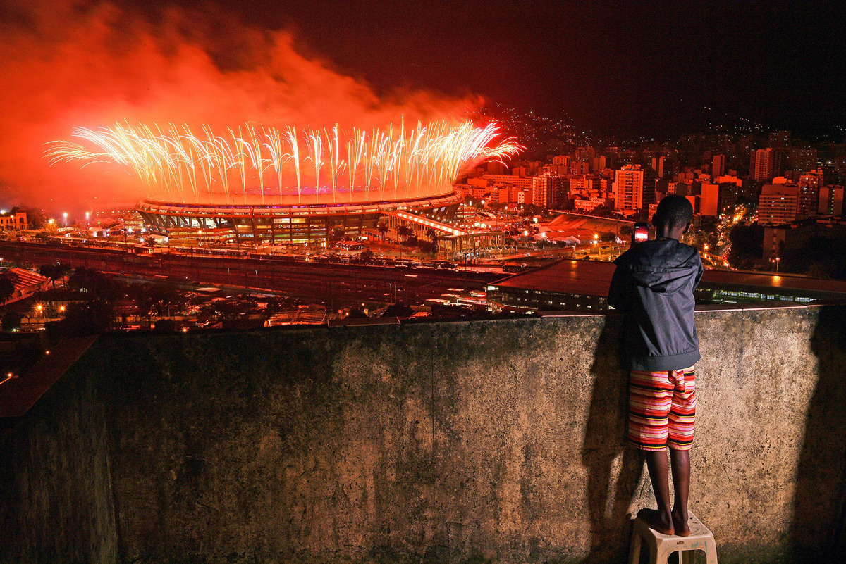 A boy from Mangueira favela watch fireworks over Maracana Stadium during the 2016 Olympics closing ceremony on August 21, 2016. Carl De Souza / AFP / Getty