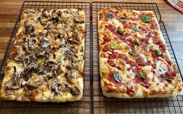 Two thin, rectangular pizzas: one with chanterelle mushrooms, one a margherita type of thing.