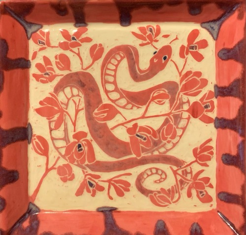 a close up of the snake tray. the snake is coiled through a few branches of orchids.