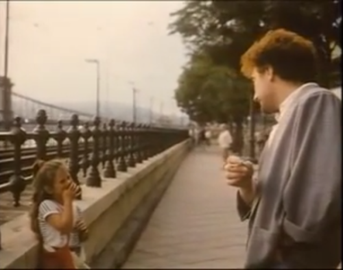 John Deacon talks to a young girl in Budapest, Hungary (1986)Girl: [says something unintelligible]De