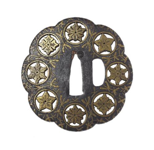 Tsuba or sword guard of iron, eight-lobed, with eight crests in brass set in openwork circles, and b