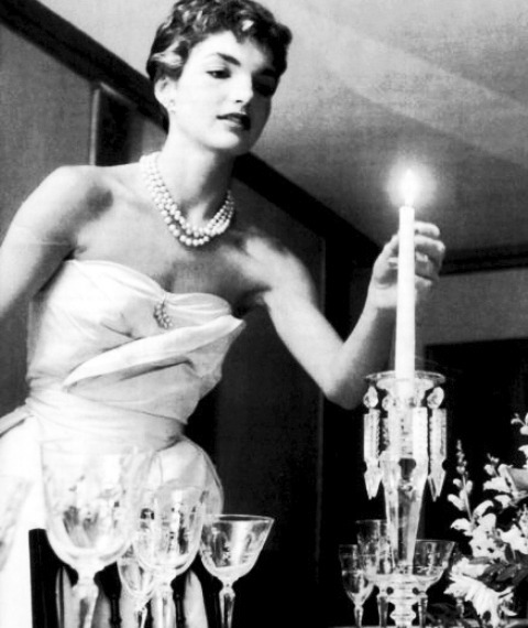 thekennedyclan: 1953, Jackie Kennedy lights candles for a dinner with friends, months after her wedd