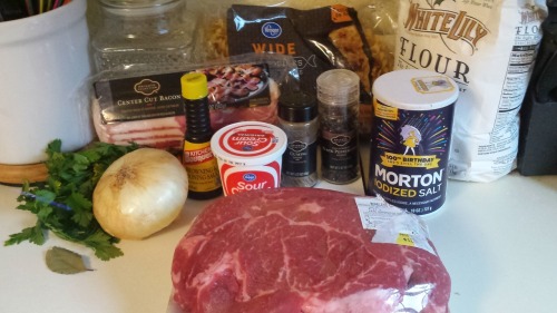 Ingredients, including parsley, bacon, onion, sour cream, noodles, flour, salt, and chuck roast.