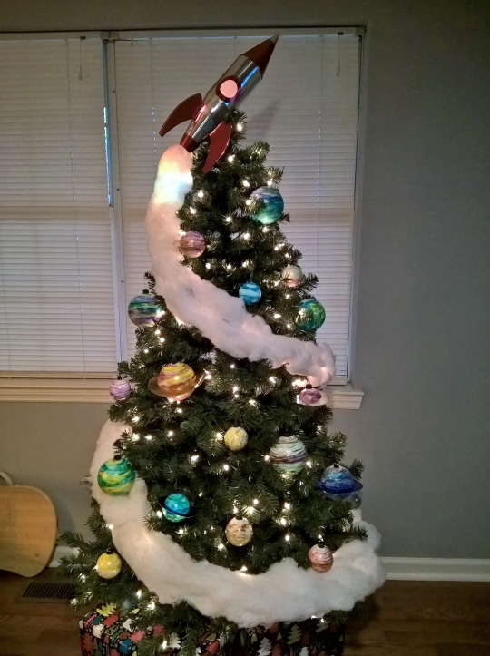 fuzzyspork: My Christmas tree! Every year I do a themed tree, and this year’s was fun to create! I made the rocket out of shiny poster board, the ornaments I got from the thrift store and repainted with glittery tempura paints to look like planets.